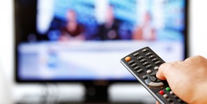 Out of focus TV LCD set and remote control in man's hand isolated over a white background.
